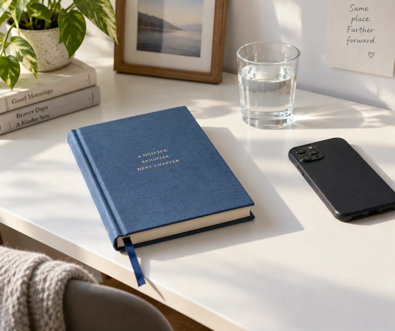 A blue clothbound journal beside a phone and glass of water.